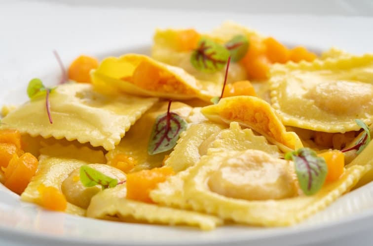 Tortelli di Zucca serviert am Teller mit jungen Rote Beete Blättern