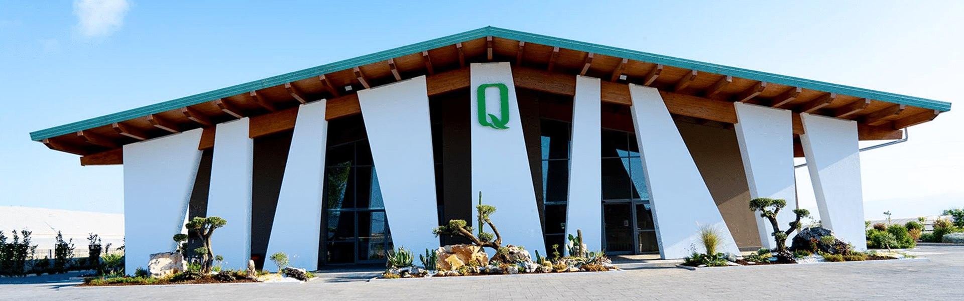 Modernes Gebäude der Olivenölmanufaktur Quattrociocchi in Italien mit stilvoller Architektur und mediterraner Bepflanzung.